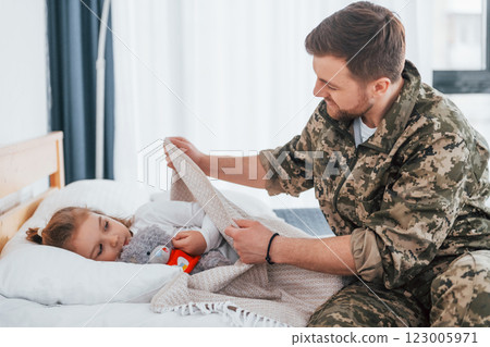 Peace and quiet. Soldier in uniform is at home with his little daughter 123005971