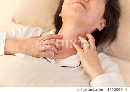 一名身穿白色睡衣的中年婦女早上在臥室出現皮膚搔癢症狀 123006044