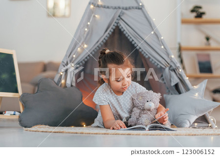 Laying down on the ground. Cute little girl playing in the tent that is in the domestic room Laying down on the ground. Cute little girl playing in the tent that is in the domestic room 123006152