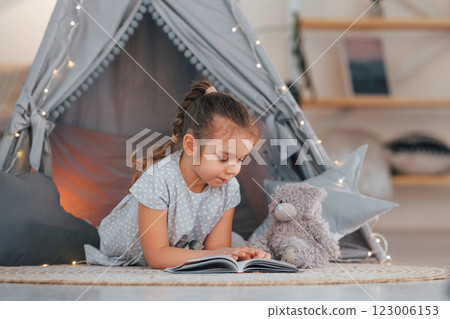 Laying down on the ground. Cute little girl playing in the tent that is in the domestic room Laying down on the ground. Cute little girl playing in the tent that is in the domestic room 123006153