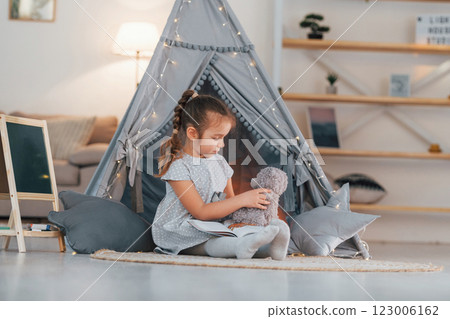 At daytime. Cute little girl playing in the tent that is in the domestic room At daytime. Cute little girl playing in the tent that is in the domestic room 123006162