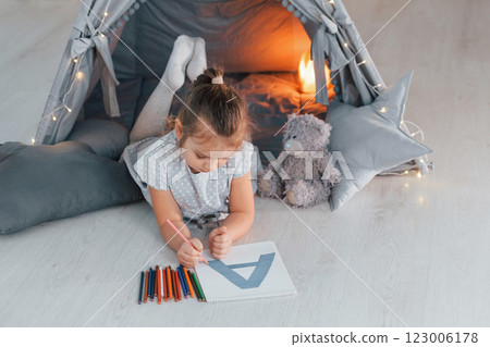Writing letter. Cute little girl playing in the tent that is in the domestic room Writing letter. Cute little girl playing in the tent that is in the domestic room 123006178