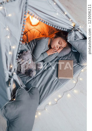 Sleep time. Cute little girl playing in the tent that is in the domestic room 123006211