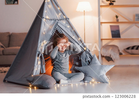 Morning time. Cute little girl playing in the tent that is in the domestic room Morning time. Cute little girl playing in the tent that is in the domestic room 123006228