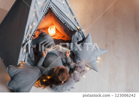 Interesting book. Cute little girl playing in the tent that is in the domestic room 123006242