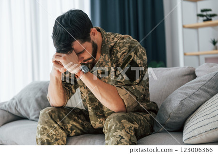 Post traumatic stress disorder. Soldier in uniform sitting indoors 123006366