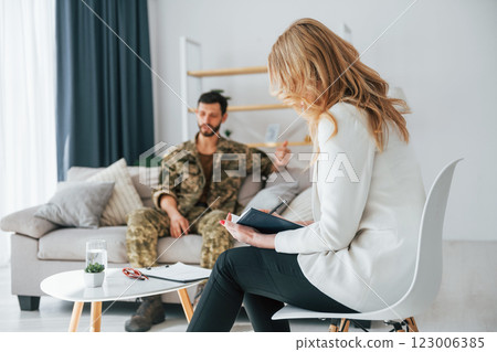 Talking to doctor. Soldier have therapy session with psychologist indoors Talking to doctor. Soldier have therapy session with psychologist indoors 123006385