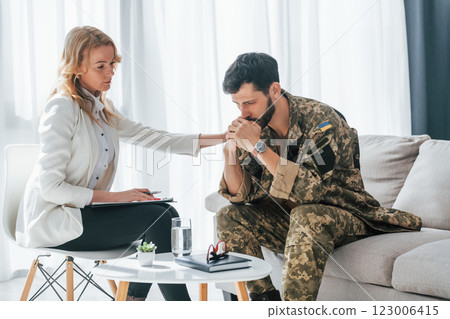 With notepad. Soldier have therapy session with psychologist indoors 123006415