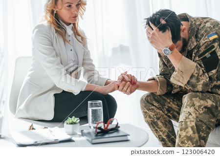 Post traumatic stress disorder. Soldier have therapy session with psychologist indoors 123006420