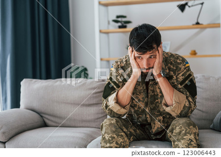 Soldier in uniform is indoors in the domestic room 123006443