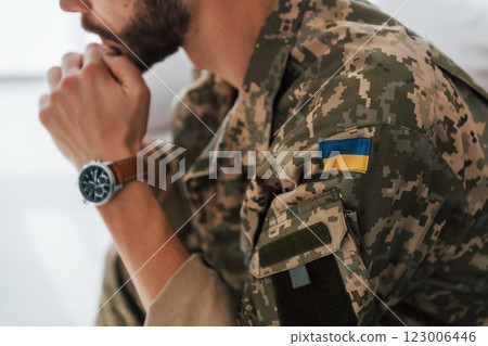 Ukrainian flag. Soldier in uniform is indoors in the domestic room Ukrainian flag. Soldier in uniform is indoors in the domestic room 123006446