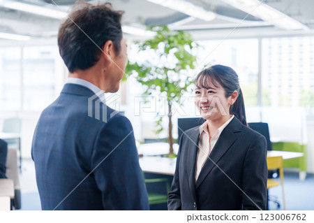Smiling young businesswoman talking to her boss Smiling young businesswoman talking to her boss 123006762
