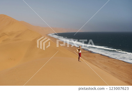 Clear blue sky. Tourist is walking on the sand near the sea Clear blue sky. Tourist is walking on the sand near the sea 123007623