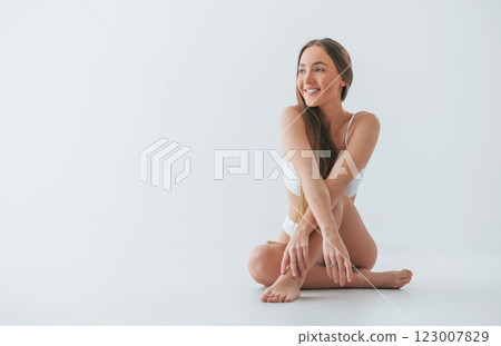 Sitting on the floor. Woman in underwear with slim body type is posing in the studio 123007829
