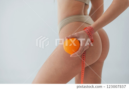 Holding orange fruit. Woman in underwear with slim body type is posing in the studio Holding orange fruit. Woman in underwear with slim body type is posing in the studio 123007837