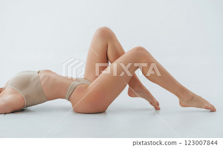 Laying down on the floor. Woman in underwear with slim body type is posing in the studio Laying down on the floor. Woman in underwear with slim body type is posing in the studio 123007844