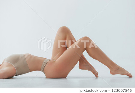 Laying down on the floor. Woman in underwear with slim body type is posing in the studio Laying down on the floor. Woman in underwear with slim body type is posing in the studio 123007846