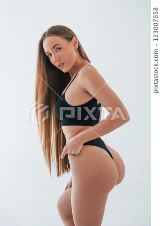 Model is against white background. Woman in underwear with slim body type is posing in the studio Model is against white background. Woman in underwear with slim body type is posing in the studio 123007858