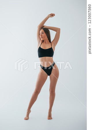 Model is against white background. Woman in underwear with slim body type is posing in the studio 123007860