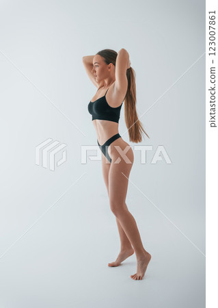 Model is against white background. Woman in underwear with slim body type is posing in the studio 123007861