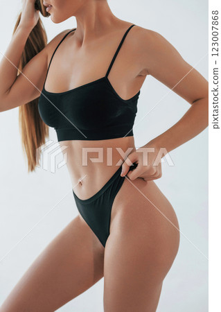 Showing new lingerie. Woman in underwear with slim body type is posing in the studio Showing new lingerie. Woman in underwear with slim body type is posing in the studio 123007868