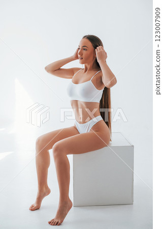 Against white colored background. Woman in underwear with slim body type is posing in the studio 123007909