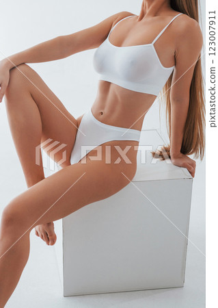 Against white colored background. Woman in underwear with slim body type is posing in the studio Against white colored background. Woman in underwear with slim body type is posing in the studio 123007911