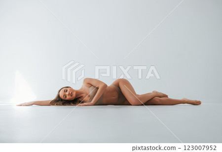 On the floor. Woman in underwear with slim body type is posing in the studio On the floor. Woman in underwear with slim body type is posing in the studio 123007952