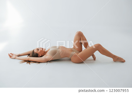 On the floor. Woman in underwear with slim body type is posing in the studio 123007955