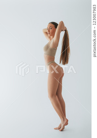 Standing and showing side. Woman in underwear with slim body type is posing in the studio Standing and showing side. Woman in underwear with slim body type is posing in the studio 123007983