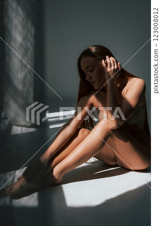 Enjoying sunlight. Woman in underwear with slim body type is posing in the studio Enjoying sunlight. Woman in underwear with slim body type is posing in the studio 123008012