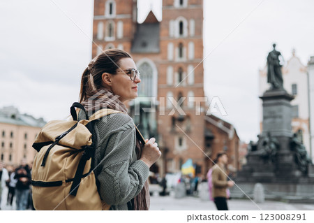 Tourist happy woman in glasses on Market Square in Krakow, Traveling Europe in autumn. St. Marys Basilica, cloudy day 123008291