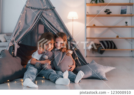 Embracing each other. Two little girls is in the tent in domestic room together Embracing each other. Two little girls is in the tent in domestic room together 123008910