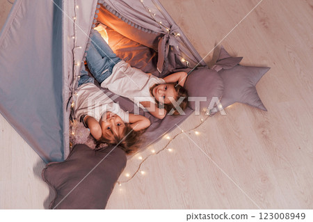 Laying down together. Two little girls is in the tent in domestic room Laying down together. Two little girls is in the tent in domestic room 123008949