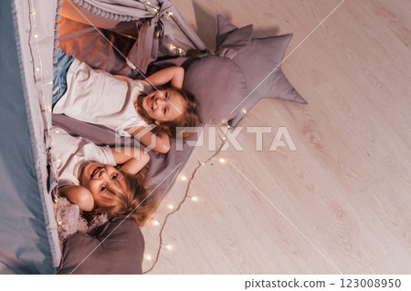 Laying down together. Two little girls is in the tent in domestic room Laying down together. Two little girls is in the tent in domestic room 123008950