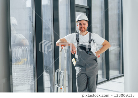 Smiling and posing. Repairman is working indoors in the modern room 123009133