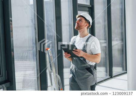 With notepad. Repairman is working indoors in the modern room With notepad. Repairman is working indoors in the modern room 123009137