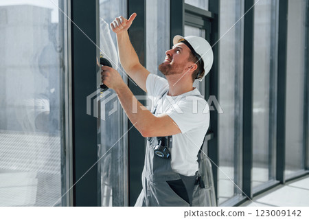 Cleaning dirty windows. Repairman is working indoors in the modern room 123009142