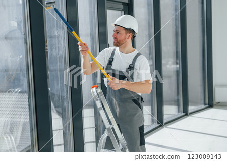 Cleaning dirty windows. Repairman is working indoors in the modern room 123009143