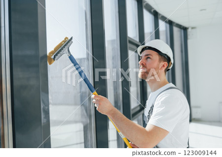 Cleaning dirty windows. Repairman is working indoors in the modern room 123009144