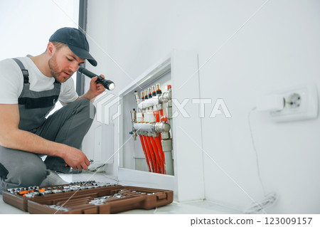 With special tools. Repairman is working indoors in the modern room 123009157
