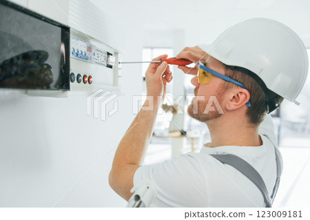 Electricity problems. Repairman is working indoors in the modern room Electricity problems. Repairman is working indoors in the modern room 123009181