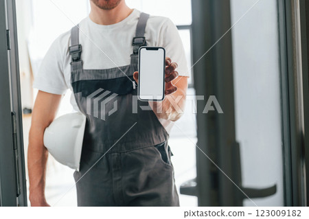 Repairman is standing indoors in the modern room 123009182