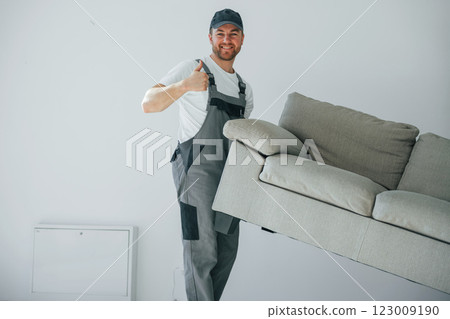 Lifting the sofa. Repairman is working indoors in the modern room Lifting the sofa. Repairman is working indoors in the modern room 123009190