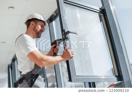 Installing new windows. Close up view of repairman that is working indoors in the modern room 123009210