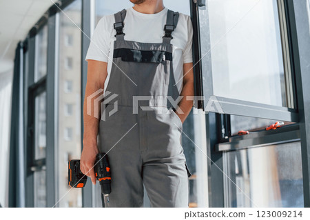 In grey uniform. Repairman is working indoors in the modern room 123009214