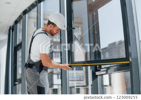 Holding window. Repairman is working indoors in the modern room 123009255