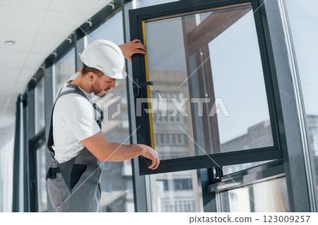 Holding window. Repairman is working indoors in the modern room Holding window. Repairman is working indoors in the modern room 123009257