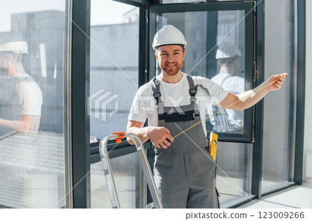 Using measure tape. Repairman is working indoors in the modern room Using measure tape. Repairman is working indoors in the modern room 123009266