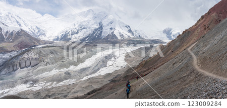 Wide panorama of valley glacier and snowy peaks with tourists hiking, Pamir mountains, Kyrgyzstan 123009284